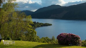 A lakeside view with a grassy area, a bench, and a table. - Foyers Lodge (Inverness)