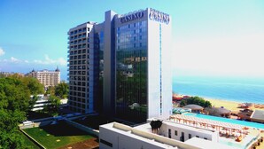 A high-rise building with a casino sign, surrounded by greenery and a pool area. - Sea View Rental Front Beach (Golden Sands)