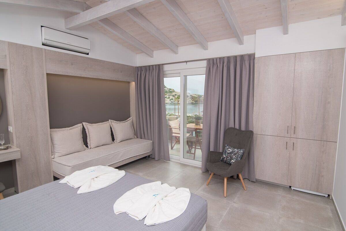 Quarto de hotel moderno com cama, sofá, poltrona e armário.