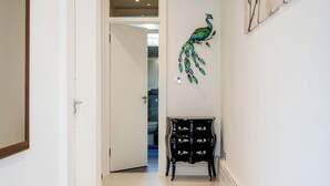 A hallway with a black cabinet, a peacock wall decoration, and a door leading to another room. - 4-bedroom Villa on Marble Arch (London)