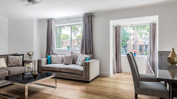 Een moderne woonkamer met een bank, salontafel en eethoek.