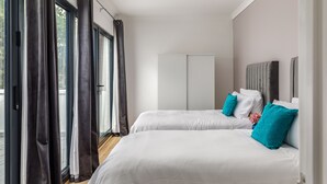 Een slaapkamer met twee bedden, een garderobe en uitzicht op het landschap.