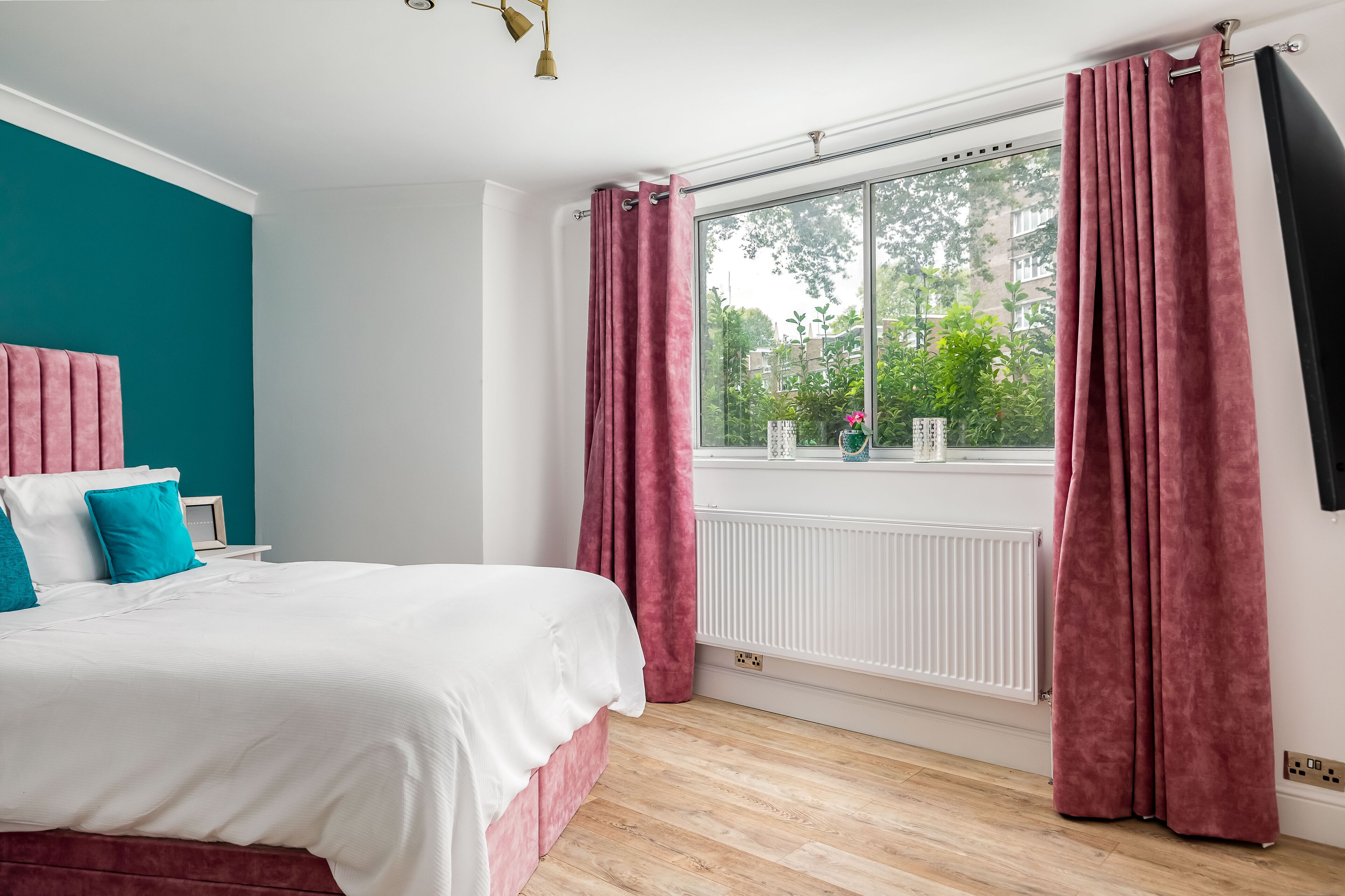 Quarto com cama grande, paredes verde-água e janela com cortinas.