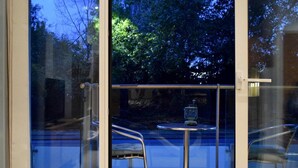 A glass door leading to an outdoor seating area with a table and chairs. - Minimal Studio With Views Over Battersea Park (London)