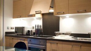 A modern kitchen with wooden cabinets, a microwave, a toaster, and a sink. - Minimal Studio With Views Over Battersea Park (London)