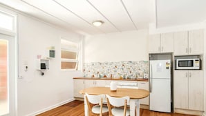 Une cuisine de taille réduite avec des meubles blancs, une table à manger en bois et des chaises.