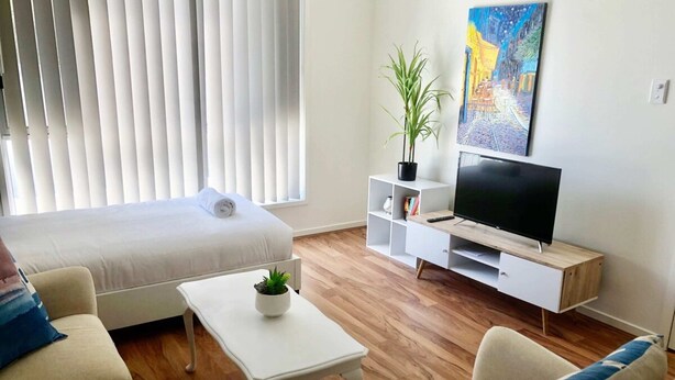 Ein modernes Wohnzimmer mit einer Couch, einem Couchtisch, einem Fernseher und einem Bücherregal.