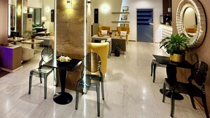 Un moderno vestíbulo de hotel con una zona de estar central, una recepción y un espejo grande en la pared.