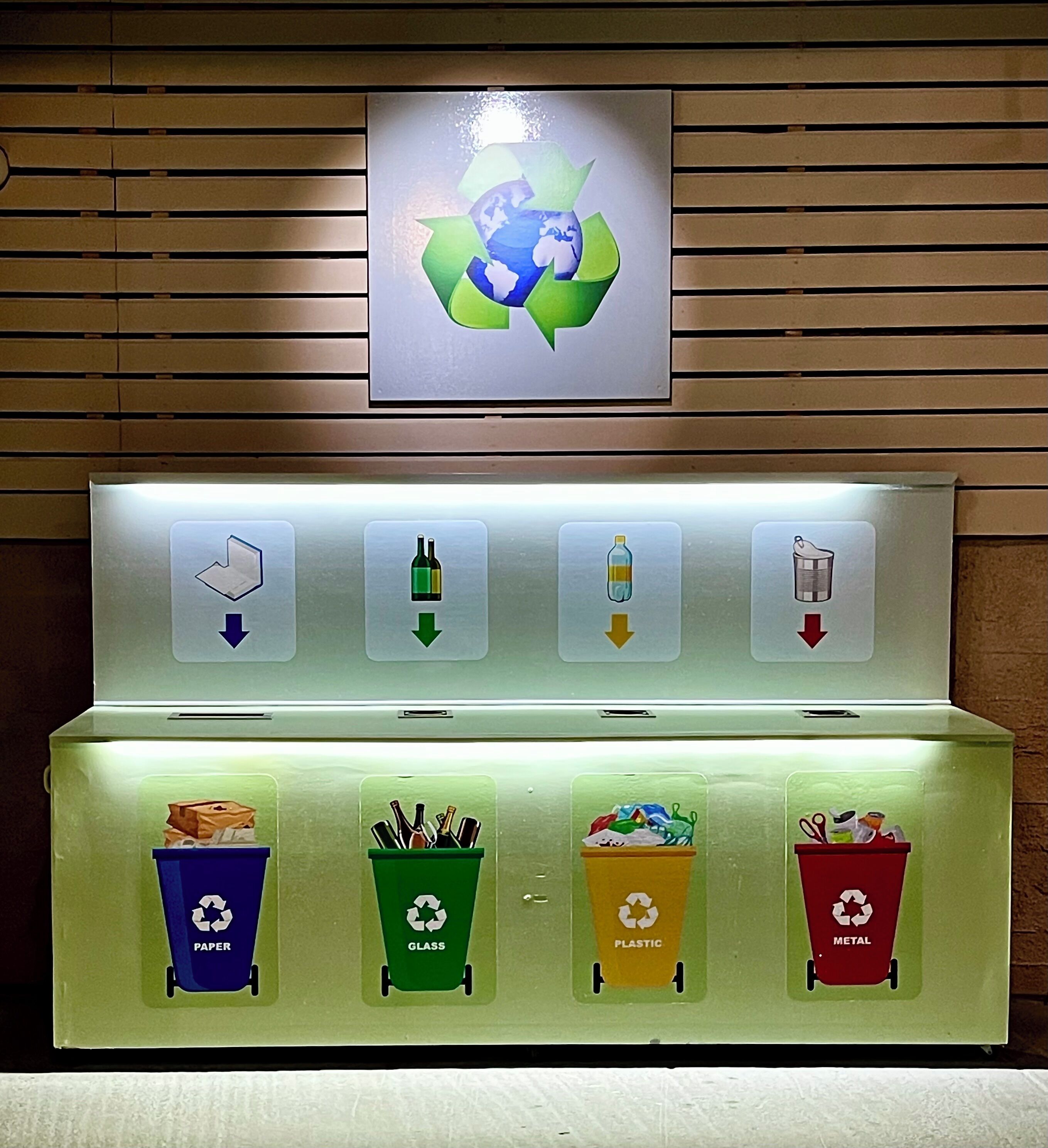Un point de collecte pour le recyclage, avec des conteneurs clairement identifiés pour le papier, le verre, le plastique et le métal.