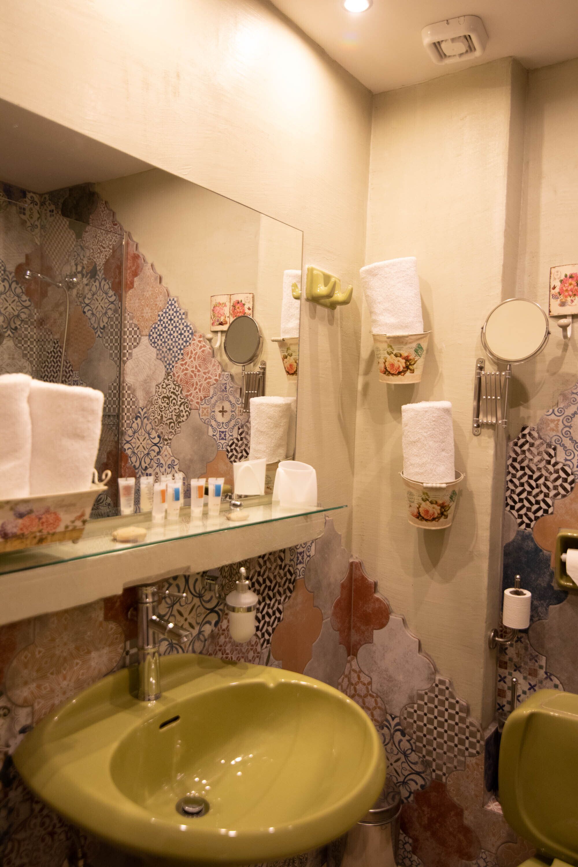 A bathroom with a green sink, a mirror, and patterned tiles.