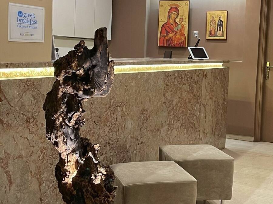 Een hotel receptie met een marmeren balie, moderne hanglampen en religieuze kunst aan de muur.