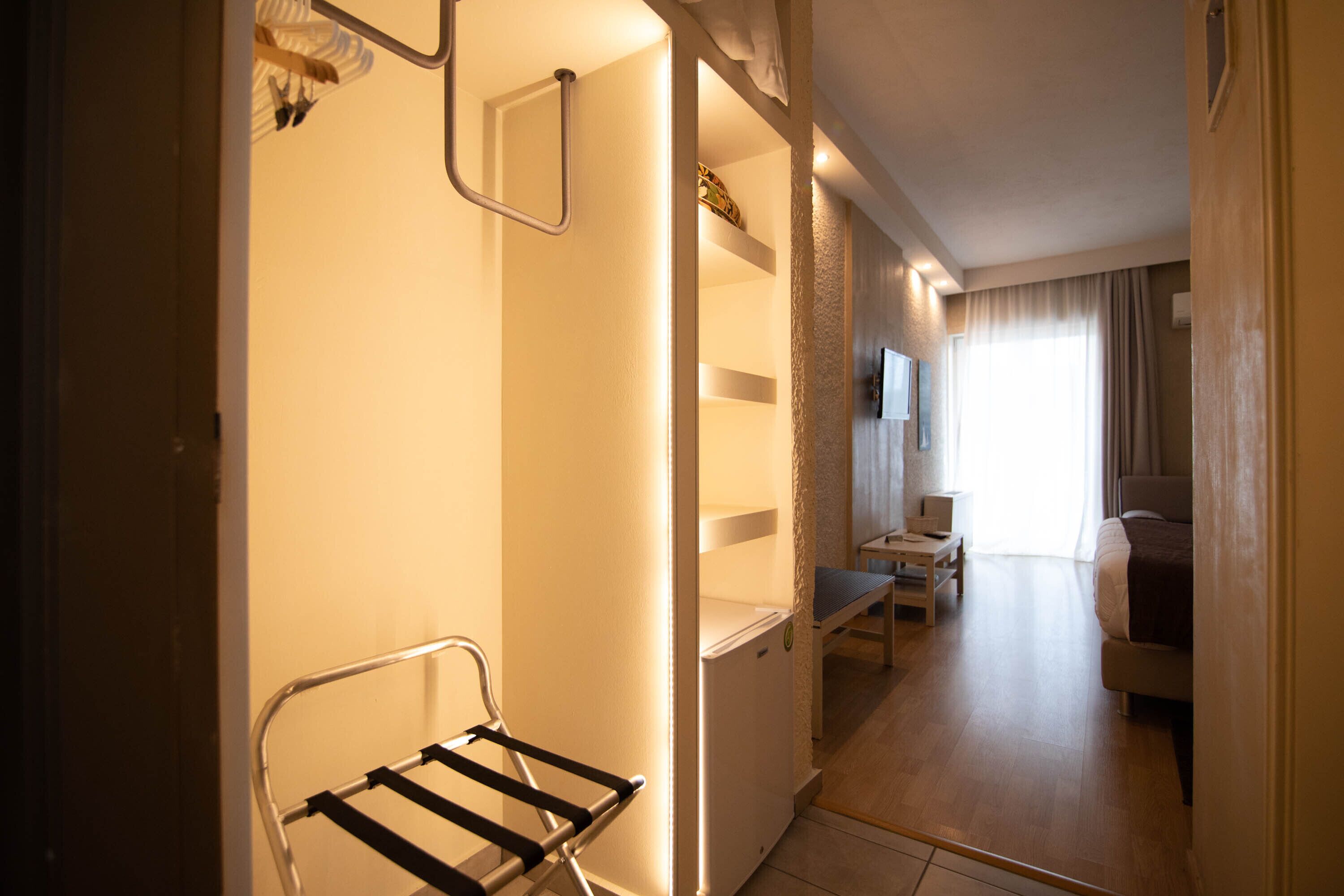 A hotel room with a bed, a desk, and a chair. There is a window with curtains and a view of the outside.