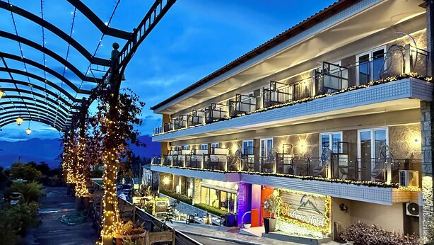 Un hotel de dos pisos con balcones, un área exterior cubierta y un letrero que indica que es el Hotel Adimios.