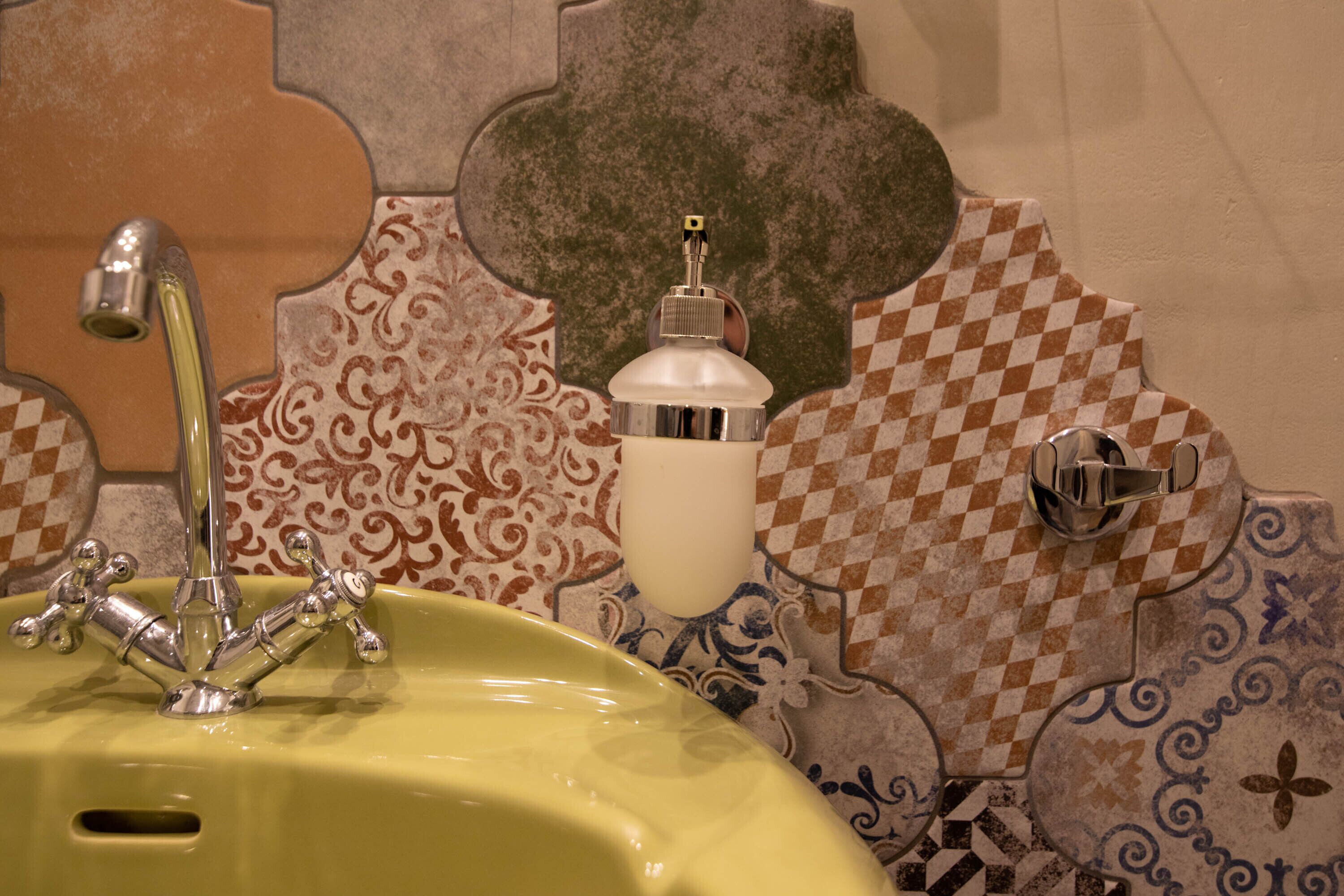A bathroom with a yellow sink, a chrome faucet, and a soap dispenser.