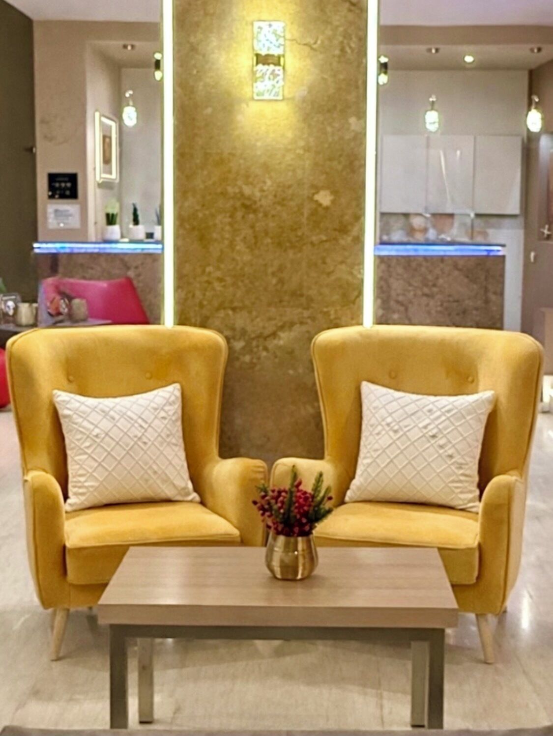 A modern living area with two yellow armchairs, a wooden coffee table, and a decorative vase.