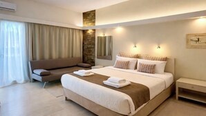 Una habitación de hotel moderna con una cama grande, un sofá, una mesita y un espejo.