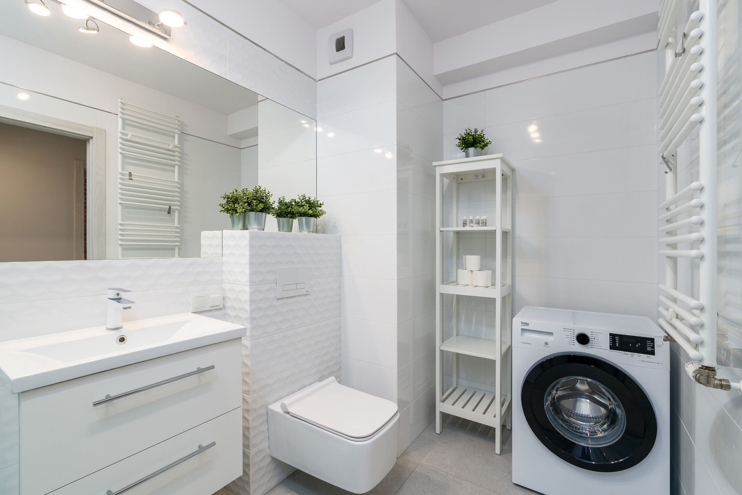 Un baño moderno con un lavamanos blanco, inodoro y lavadora integrada.