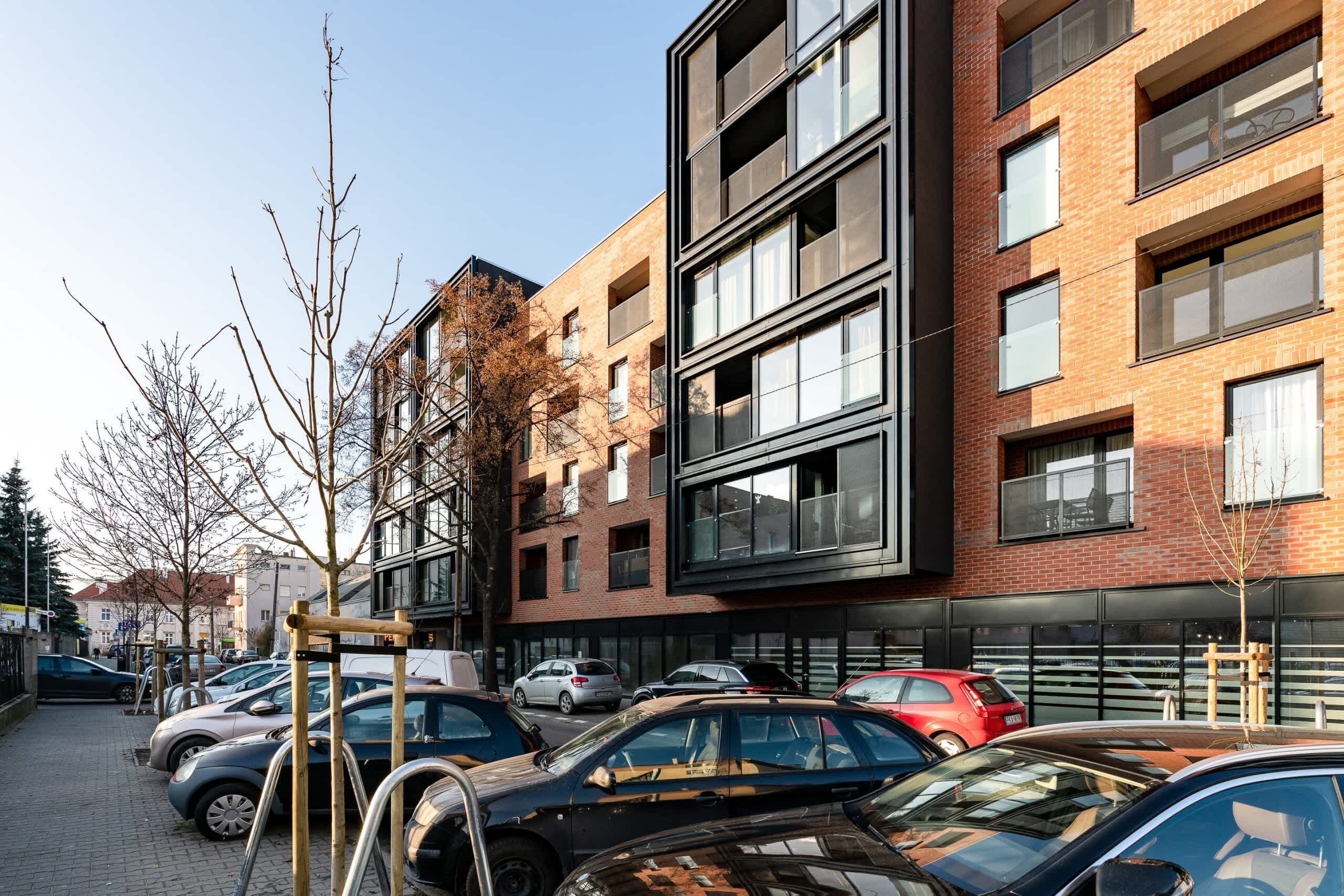A multi-story building with a modern architectural design, featuring large windows and a brick facade.