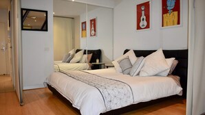 Une chambre moderne avec un grand lit, un miroir et des œuvres d’art accrochées aux murs.