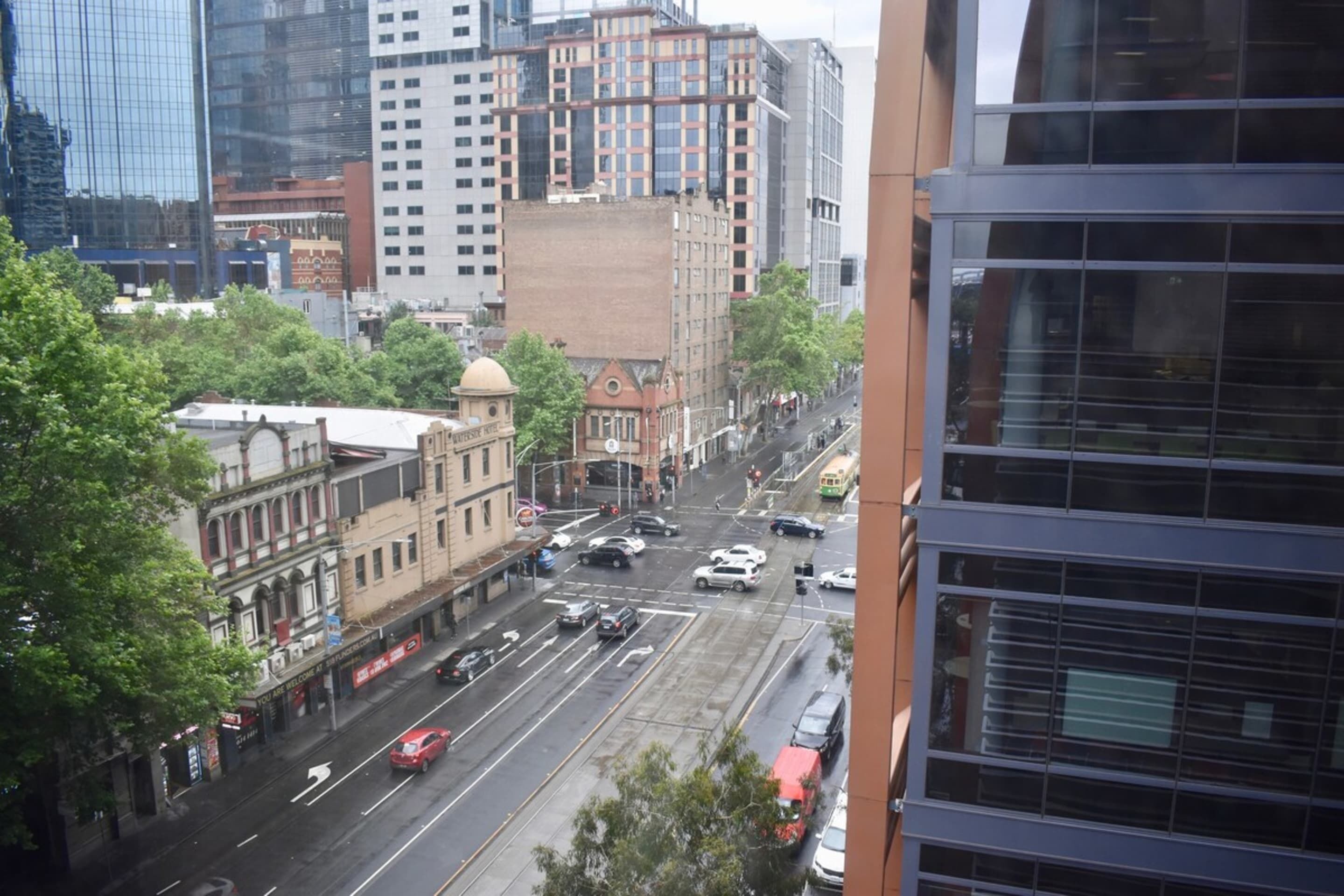 A city street with buildings, cars, and a tram.