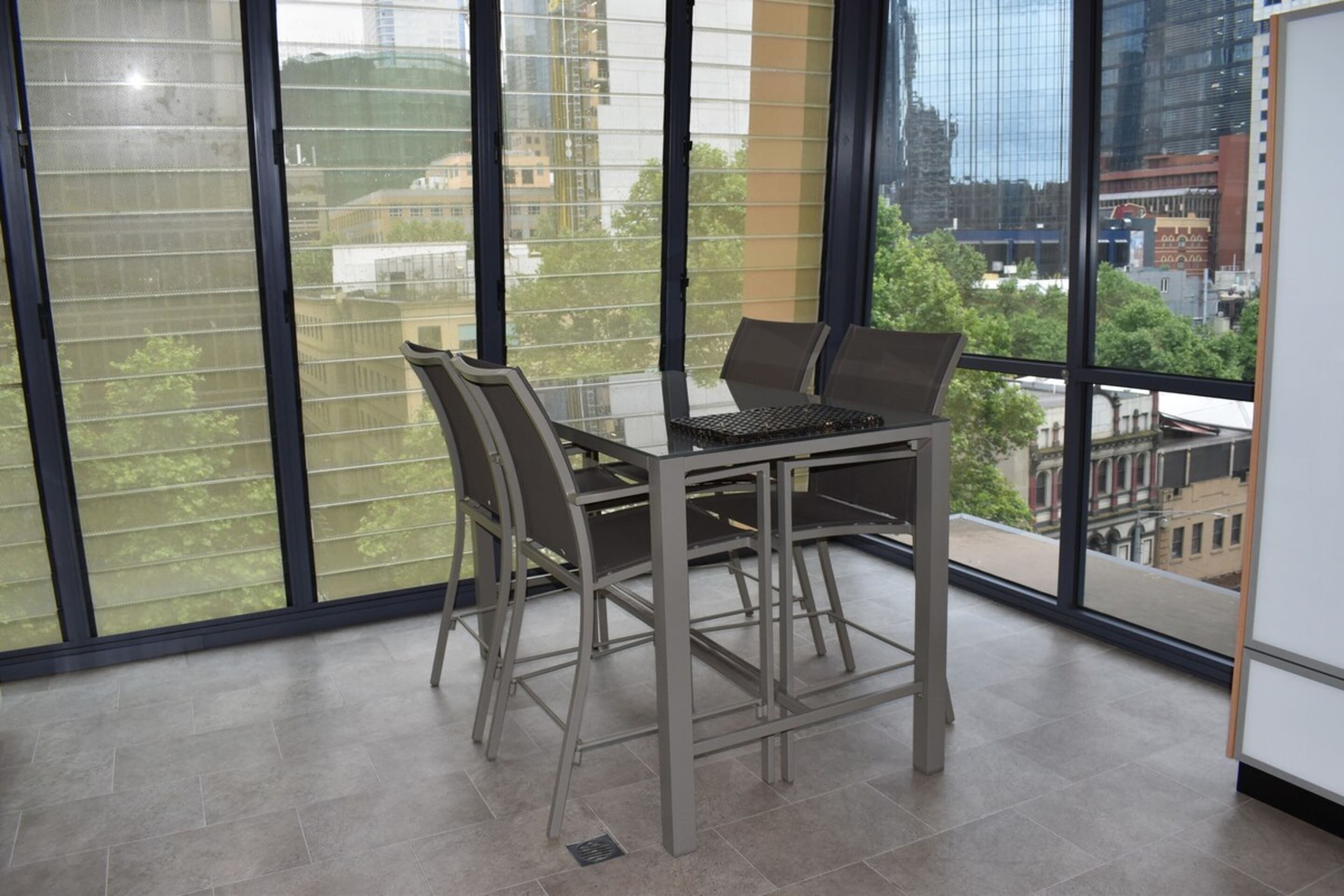 A modern office space with a glass wall, a table with chairs, and a laptop.