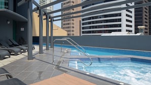 A rooftop pool area with a metal ladder, lounge chairs, and a tiled pool. - 1 Bedroom Studio Apartment near Eagle Street (Brisbane)