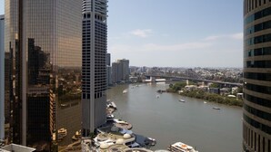 A high-rise building with a curved facade and a river with boats in the background. - 1 Bedroom Studio Apartment near Eagle Street (Brisbane)