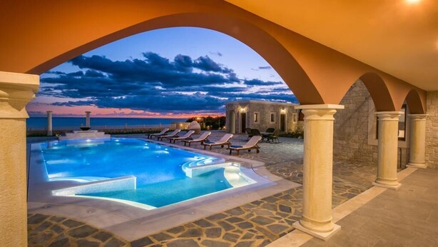 Ein Swimmingpool mit Liegestühlen und Blick auf den Sonnenuntergang.