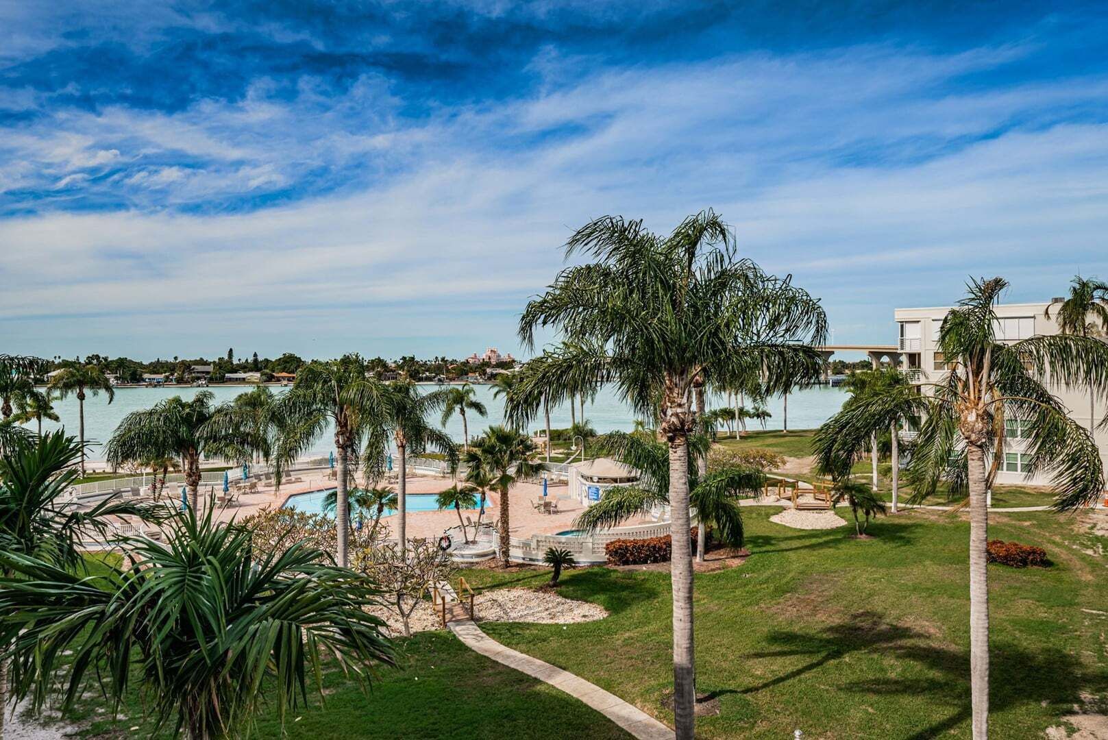 Un resort con piscina, palmeras y vista al océano.