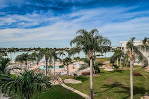 A resort with a pool, palm trees, and a view of the ocean.