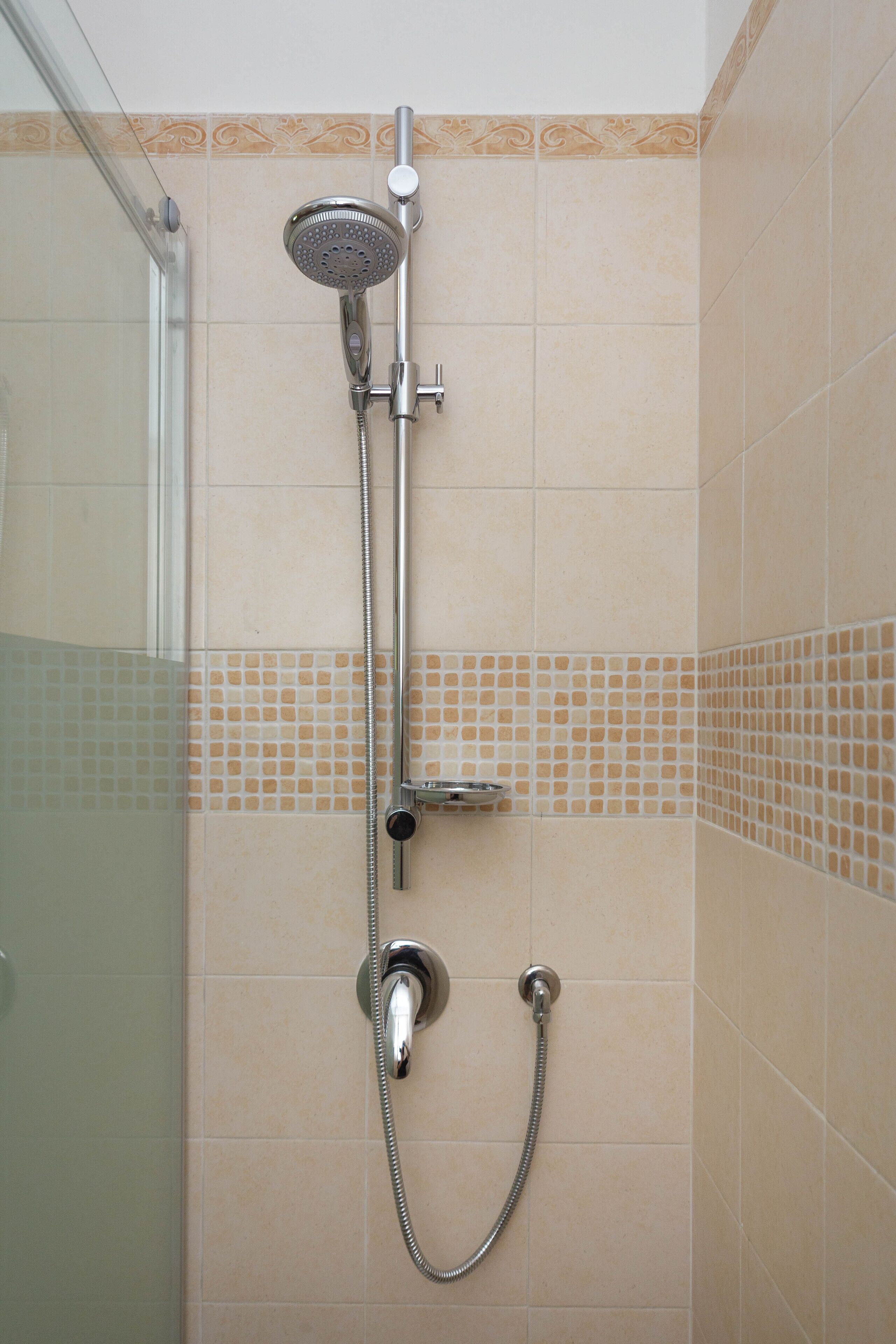 A shower with a handheld showerhead and a handheld hose.