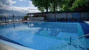 En swimmingpool med liggestole og et overdækket område.