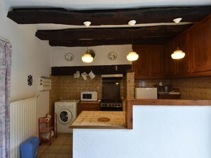A compact kitchen with a washing machine, microwave, and stove.