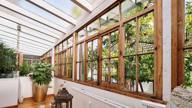 A conservatory with wooden-framed windows, a radiator, and potted plants. - Apartment in the half-timbered courtyard 'house in motion' (Neunkirchen-Seelscheid)