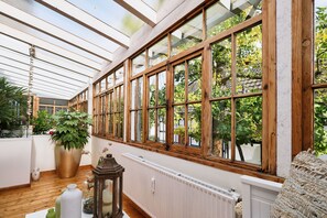 Un invernadero con ventanas de madera, un radiador y plantas en macetas.