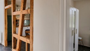 A room with a wooden beam structure, a white door, and a tiled floor. - Apartment in the half-timbered courtyard 'house in motion' (Neunkirchen-Seelscheid)