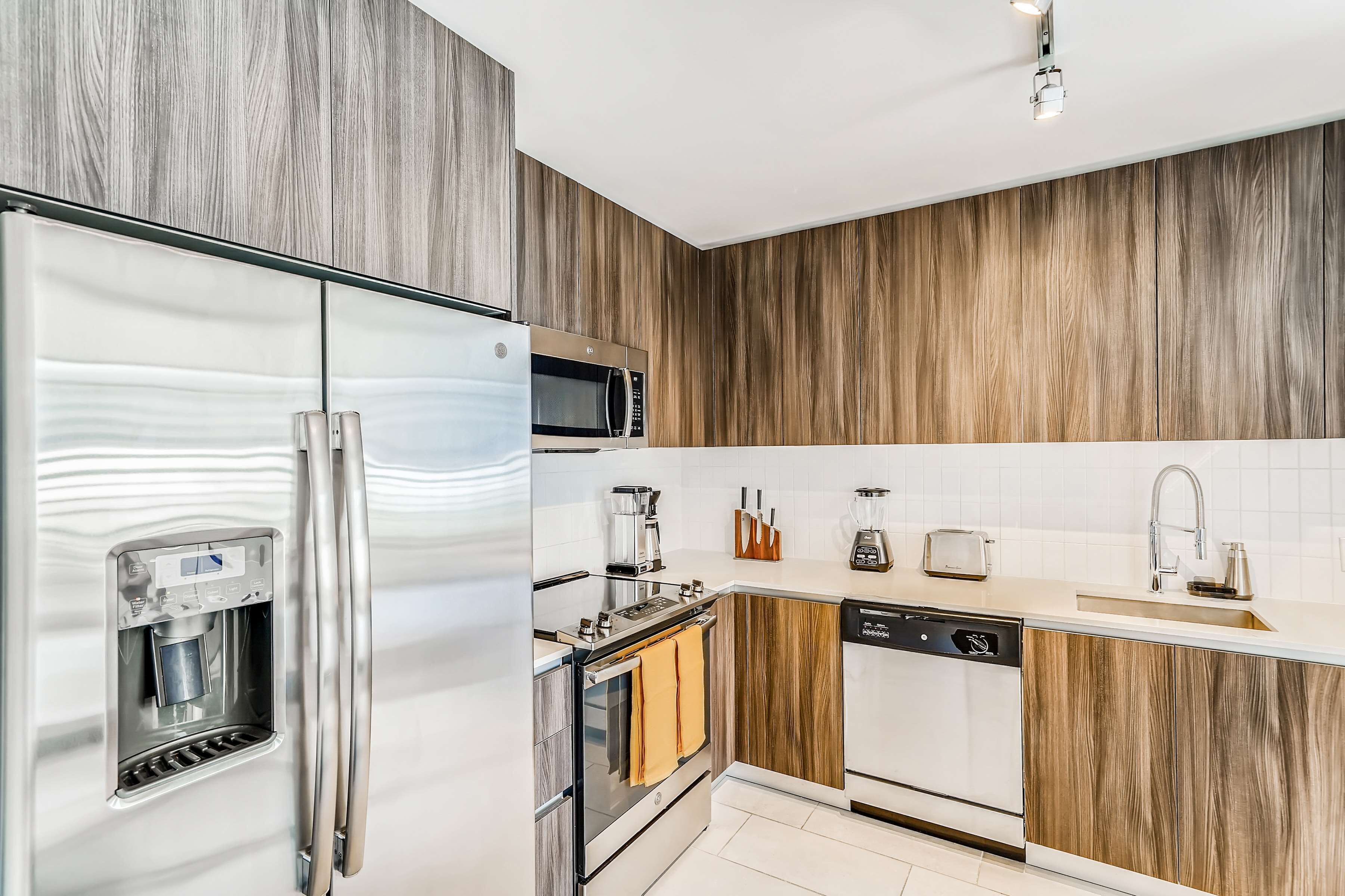 Een moderne keuken met een roestvrijstalen koelkast, een ingebouwde magnetron en een waterdispenser.