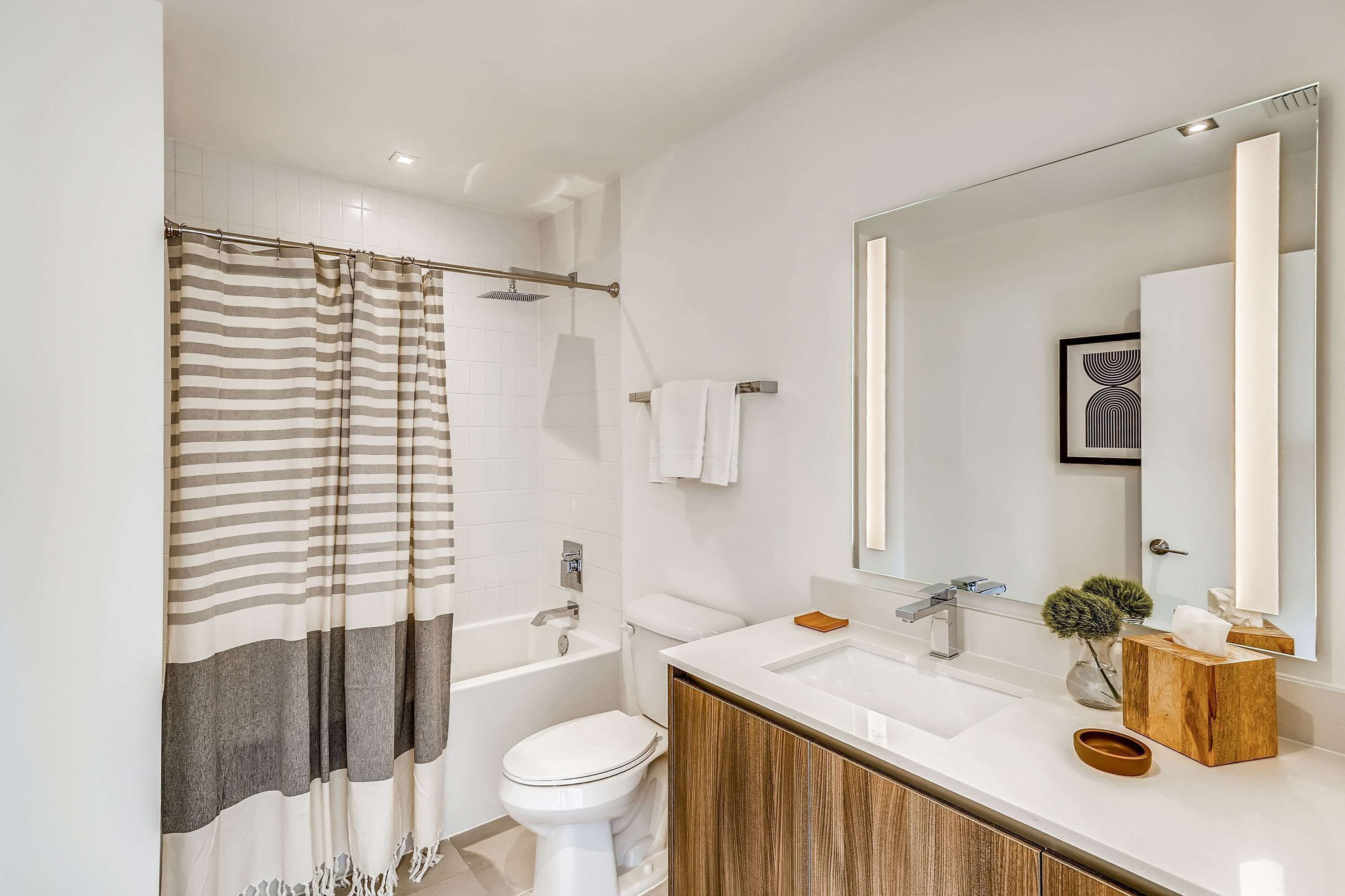 A modern bathroom with a bathtub, toilet, and vanity with a mirror.