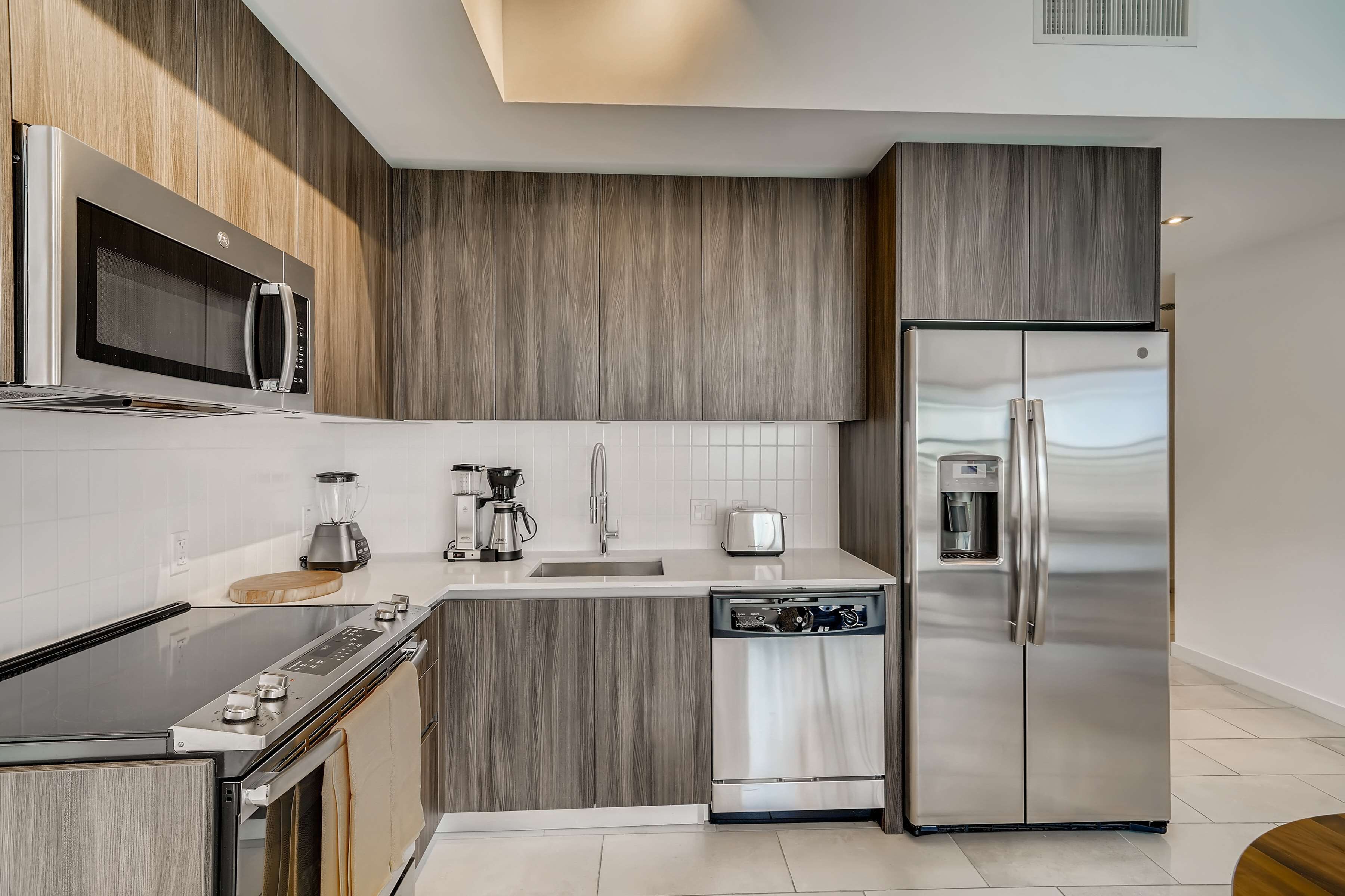 Una cocina moderna con microondas integrado, refrigerador de acero inoxidable y lavavajillas.