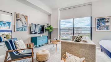 Un salon moderne avec une grande fenêtre, un meuble bleu, un canapé gris et une chaise bleue.