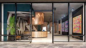 A modern reception area with a wooden reception desk, a large abstract painting, and a potted plant. - Sentral Wynwood (Miami)