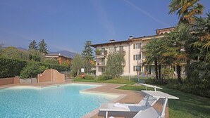 A swimming pool with lounge chairs and a lifebuoy, surrounded by greenery and buildings. - Il Cedro - near to the old town of Salò with pool (Salò)