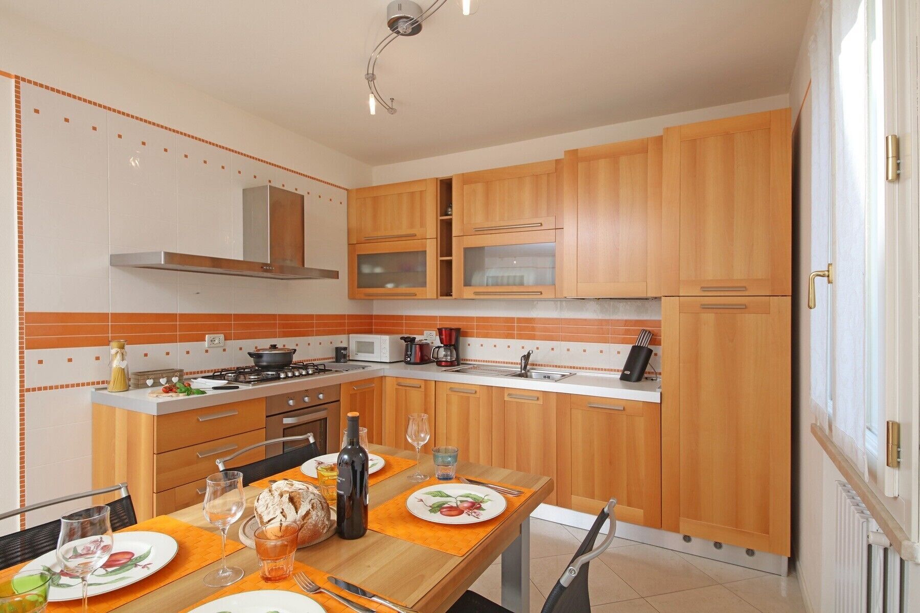 A modern kitchen with wooden cabinets, a gas stove, a microwave, and a refrigerator.