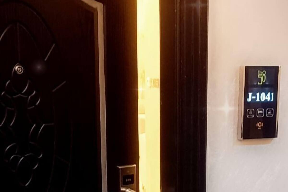 A hotel room entrance with a modern door, a digital keycard reader, and a room number sign.