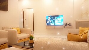 A modern living room with two sofas, a coffee table, and a flat-screen TV mounted on the wall. - The 58 Hotel Mahboula (Mahboula)