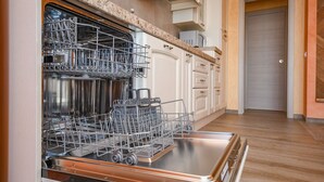 A kitchen with a dishwasher, wooden cabinets, and a wooden floor.