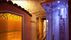 A hotel bathroom with a shower, a tiled wall, and a door with a handle.