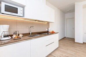 A modern kitchen with a built-in microwave, coffee maker, and a double sink. - Orange House with breathtaking lake view (Tignale)