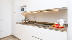 A modern kitchen with white cabinets, a stainless steel sink, a microwave, and a coffee maker. - Orange House with breathtaking lake view (Tignale)