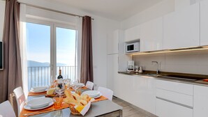 A modern kitchen with white cabinets, a microwave, and a coffee maker. - Orange House with breathtaking lake view (Tignale)